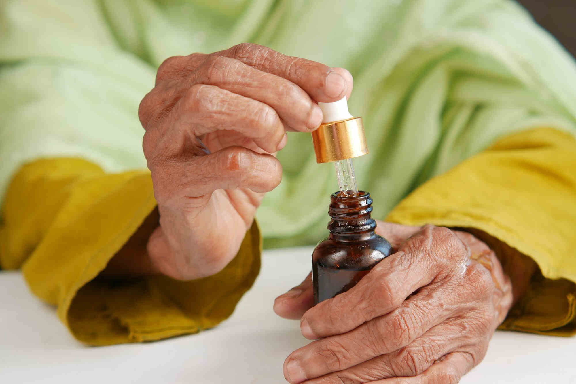 Idős nő CBD olajat használ Parkinson tünetek enyhítésére